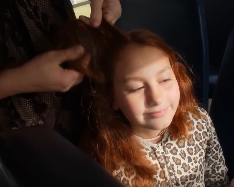 A bus driver assists a little girl with braiding her hair after the death of her mother